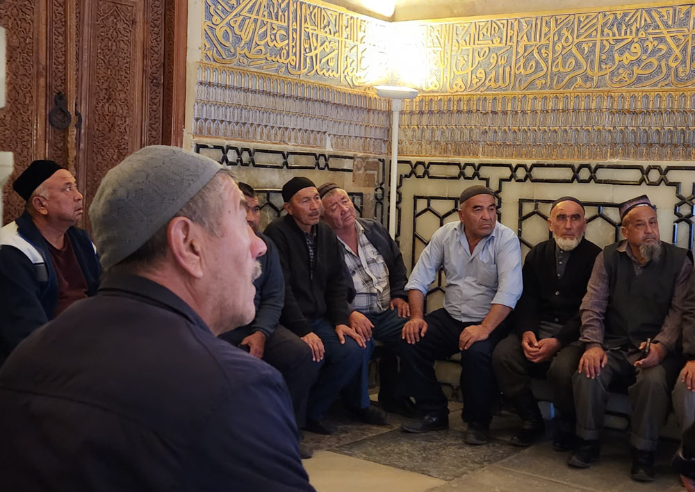 Men listening to Imam chant inside tomb of Tamerlane, Samarkand.