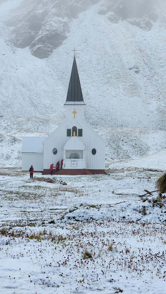 A church with people standing outside in the snow.